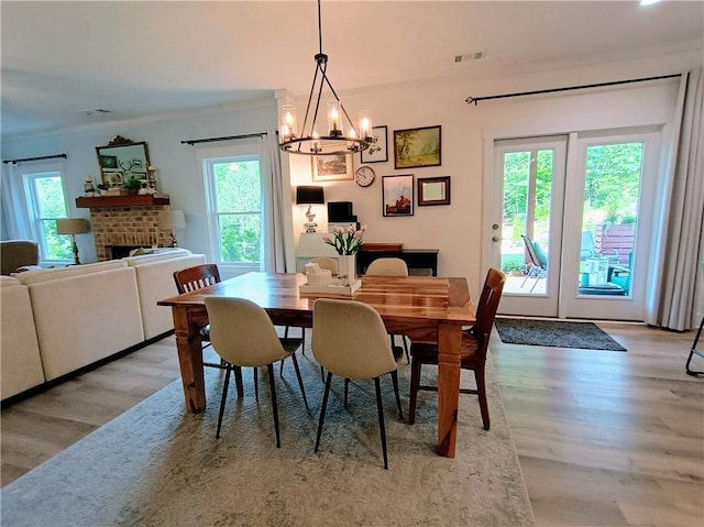 336 White Oak Way, Monroe, GA 30655 - dining area with wood finished floors, plenty of natural light, ornamental molding, a chandelier, and a brick fireplace