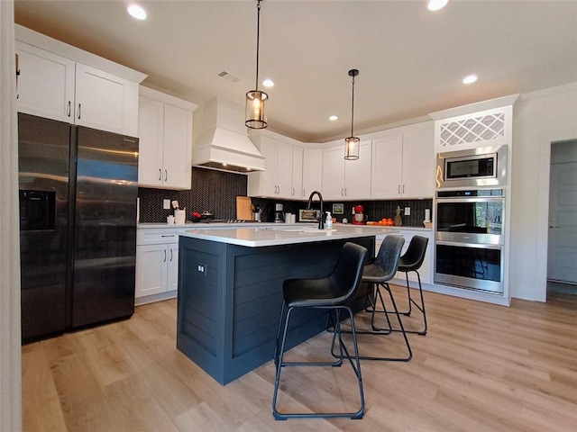 336 White Oak Way, Monroe, GA 30655 - kitchen with appliances with stainless steel finishes, custom range hood, white cabinetry, a kitchen island with sink, and recessed lighting