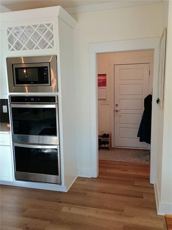 336 White Oak Way, Monroe, GA 30655 - kitchen featuring stainless steel appliances, light wood finished floors, baseboards, and white cabinetry