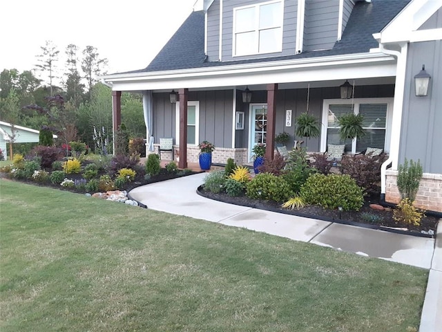 336 White Oak Way, Monroe, GA 30655 - view of exterior entry featuring board and batten siding, covered porch, a yard, brick siding, and a shingled roof