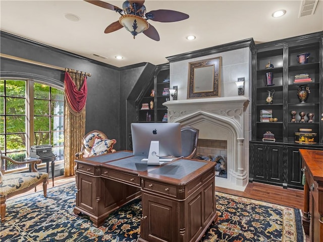 office space featuring visible vents, a fireplace, crown molding, and wood finished floors