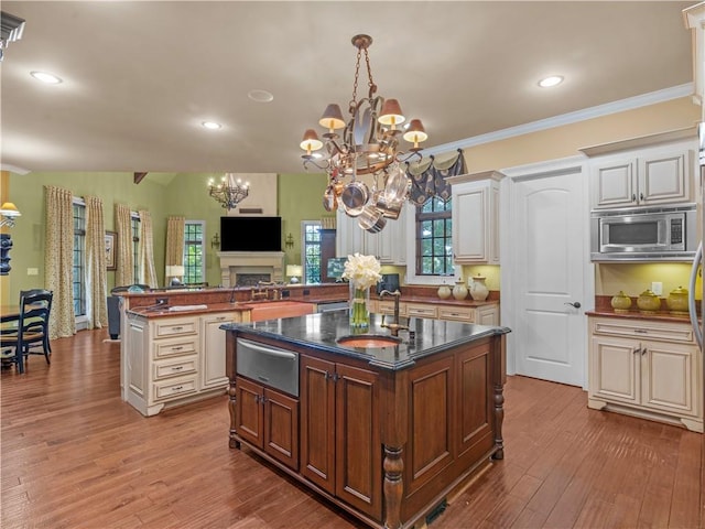 kitchen with a warming drawer, ornamental molding, a sink, stainless steel microwave, and wood finished floors