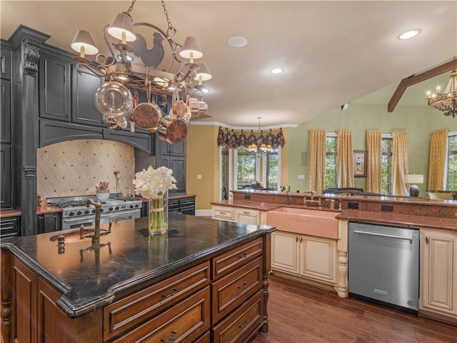 kitchen with a sink, cream cabinets, appliances with stainless steel finishes, and a chandelier