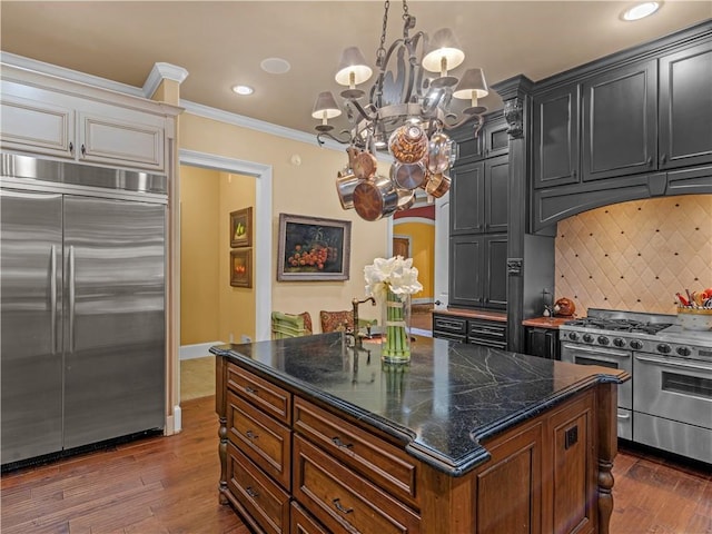 kitchen featuring decorative backsplash, high end appliances, dark wood-style floors, and ornamental molding