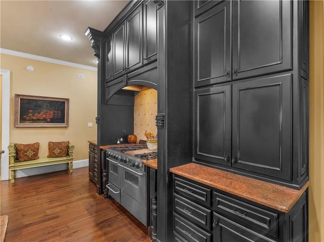 kitchen featuring crown molding, baseboards, range with two ovens, dark wood-style flooring, and dark cabinets