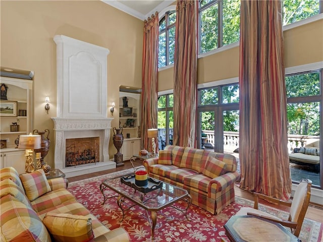 living area with crown molding, a fireplace with raised hearth, and a towering ceiling