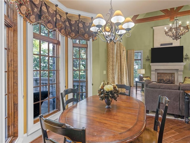 dining room featuring ornamental molding, a fireplace, an inviting chandelier, and wood finished floors