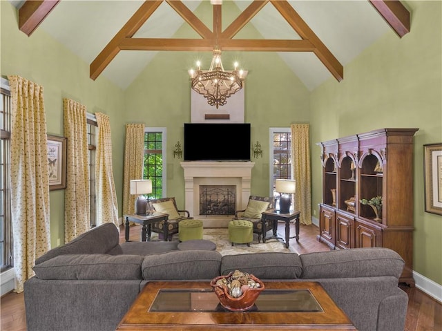 living room with beam ceiling, a fireplace with raised hearth, an inviting chandelier, and wood finished floors