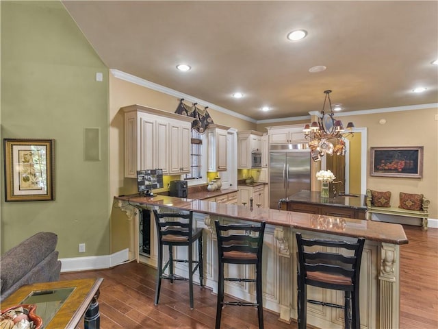 kitchen with built in appliances, a kitchen breakfast bar, dark wood-type flooring, and ornamental molding