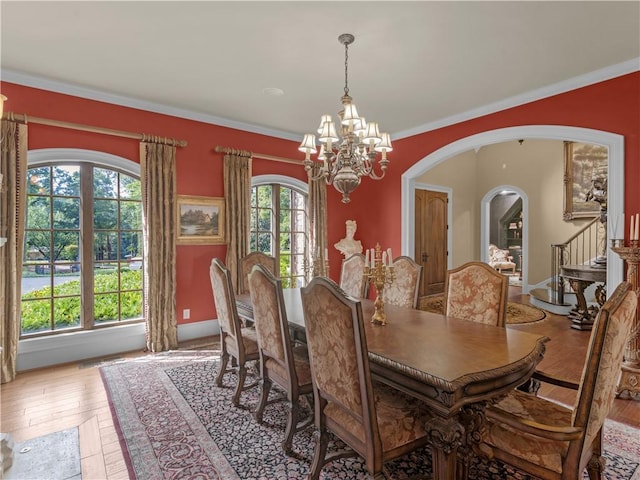 dining area with light wood-style flooring, arched walkways, and a wealth of natural light