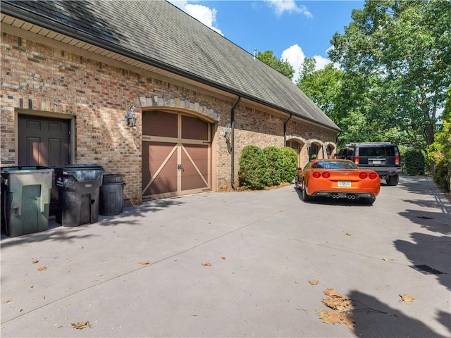 view of home's exterior featuring brick siding, driveway, and a shingled roof