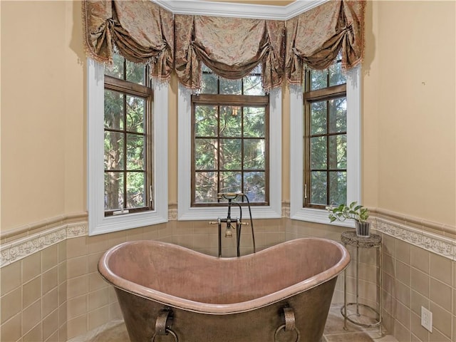 full bathroom with a soaking tub, wainscoting, and tile walls