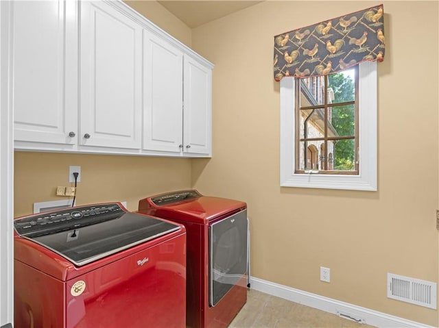 clothes washing area featuring tile patterned floors, visible vents, washer and dryer, cabinet space, and baseboards