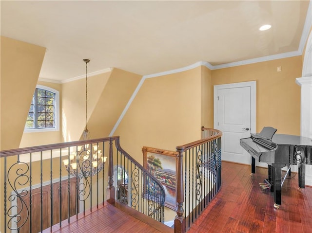 hallway featuring wood-type flooring, an inviting chandelier, an upstairs landing, and crown molding