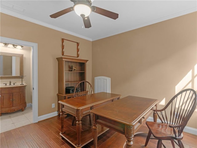 dining room with light wood finished floors, a ceiling fan, baseboards, and ornamental molding