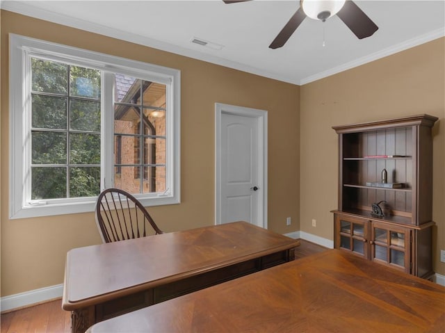 office area with wood finished floors, visible vents, baseboards, ceiling fan, and ornamental molding