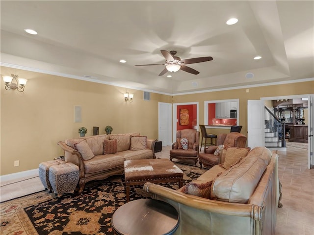 living room featuring stairs, a raised ceiling, recessed lighting, and ceiling fan with notable chandelier