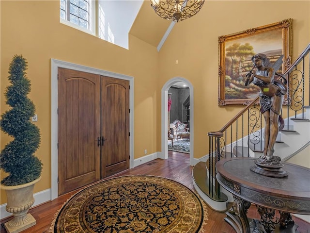 foyer entrance featuring stairs, wood finished floors, and arched walkways