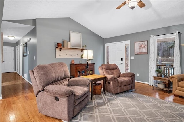 living room featuring light wood-style floors, ceiling fan, baseboards, and vaulted ceiling