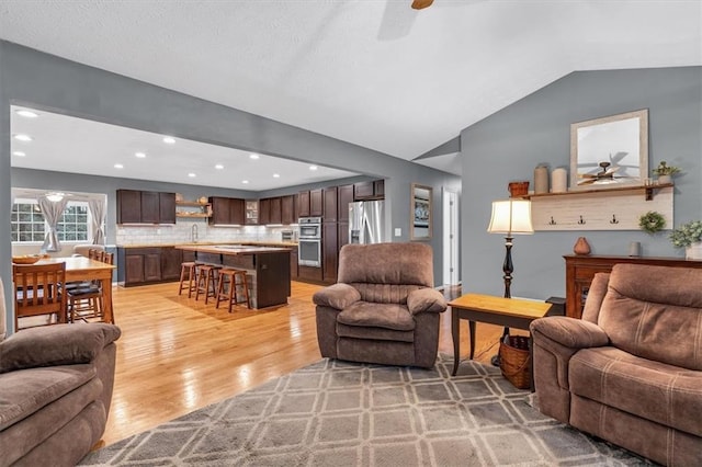 living room featuring a ceiling fan, light wood-style floors, vaulted ceiling, and recessed lighting