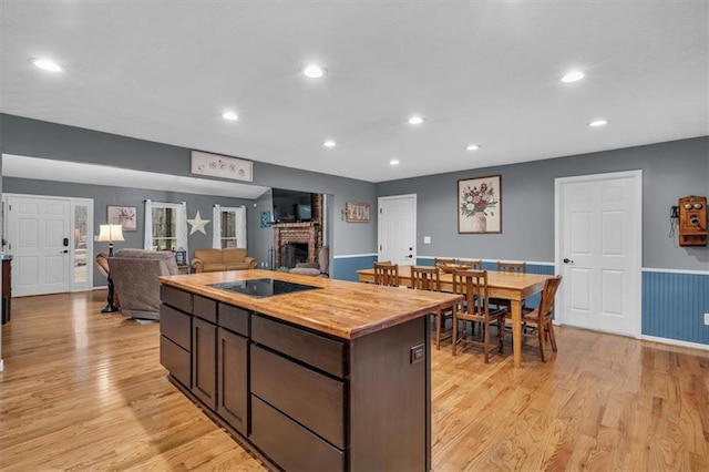 kitchen with a fireplace, light wood finished floors, recessed lighting, wood counters, and black electric cooktop