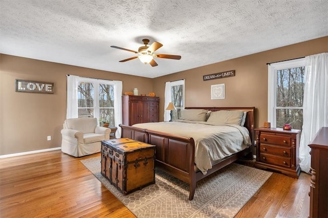 bedroom featuring a textured ceiling, baseboards, and wood finished floors