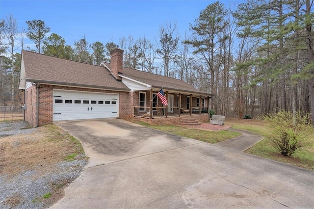 view of front of home with brick siding, a chimney, a porch, a garage, and driveway