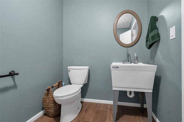 half bathroom featuring vanity, wood finished floors, toilet, and baseboards