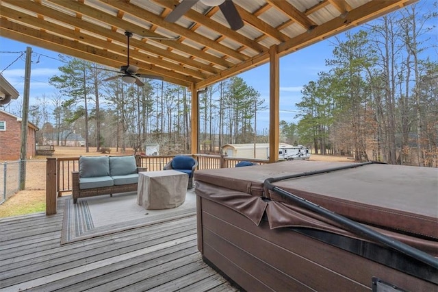 wooden deck with an outdoor hangout area, ceiling fan, a hot tub, and fence