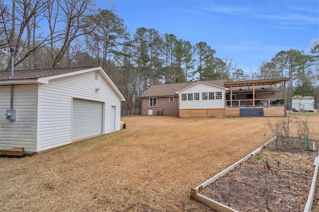 view of yard with a garage, a garden, dirt driveway, and an outbuilding