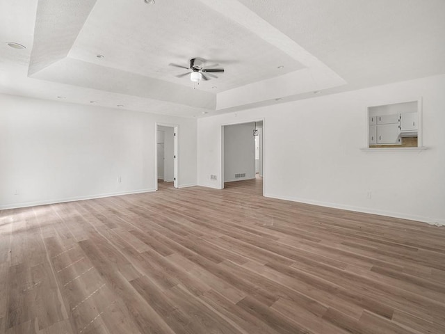 interior space with ceiling fan, baseboards, and a raised ceiling