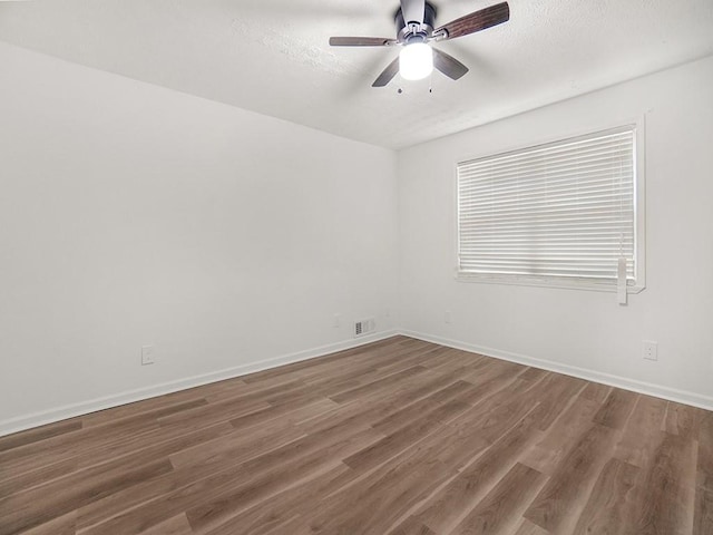 empty room with visible vents, wood finished floors, baseboards, ceiling fan, and a textured ceiling