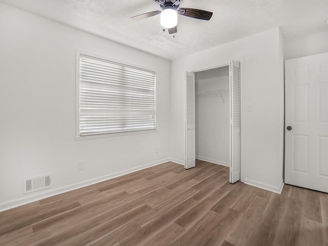 unfurnished bedroom with visible vents, a closet, wood finished floors, baseboards, and a textured ceiling