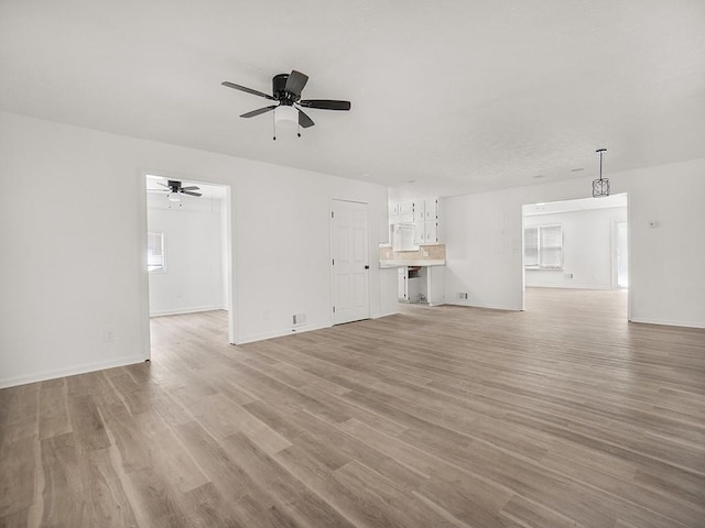 unfurnished living room with a ceiling fan, baseboards, and light wood-type flooring
