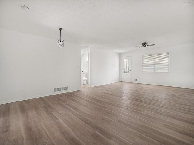 unfurnished living room featuring visible vents, a ceiling fan, baseboards, and wood finished floors