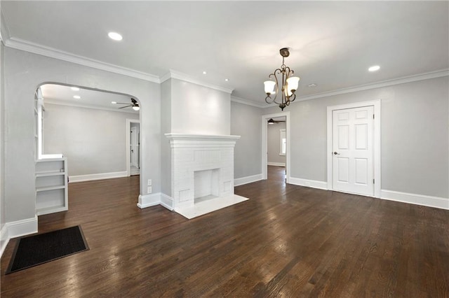 unfurnished living room featuring crown molding, a brick fireplace, ceiling fan with notable chandelier, and dark hardwood / wood-style floors