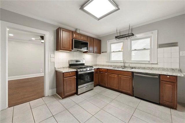 kitchen featuring tasteful backsplash, sink, ornamental molding, light tile patterned floors, and stainless steel appliances