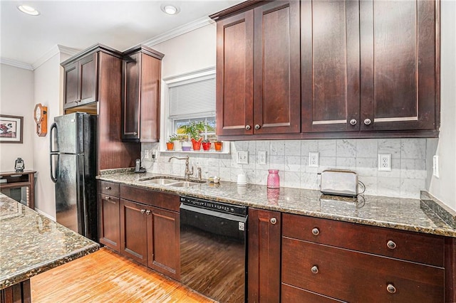 kitchen with a sink, black appliances, ornamental molding, and dark stone countertops