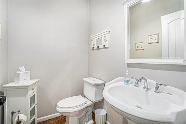 bathroom featuring a sink, baseboards, toilet, and wood finished floors