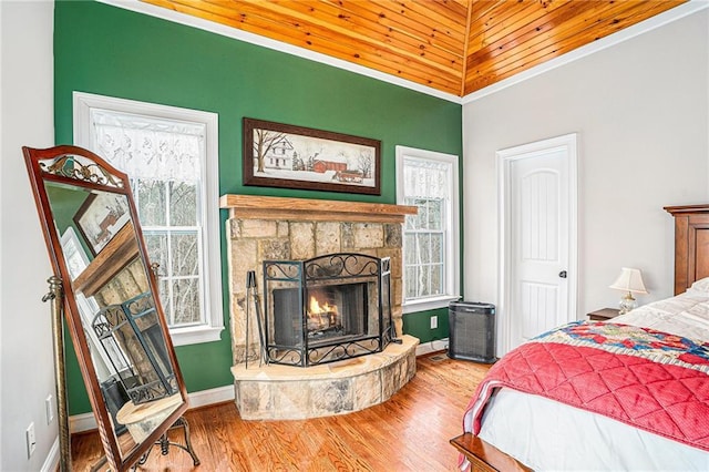 bedroom featuring a stone fireplace, baseboards, and wood finished floors