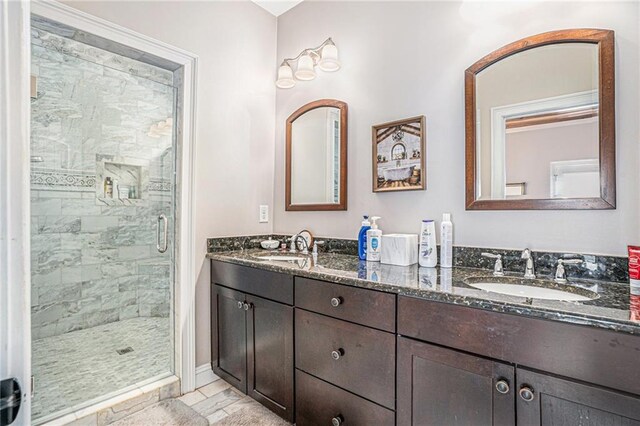 full bathroom with a sink, double vanity, and a shower stall