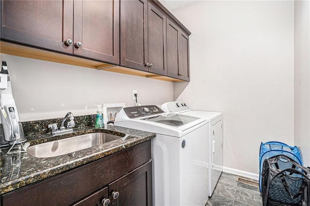 washroom with a sink, baseboards, cabinet space, and separate washer and dryer