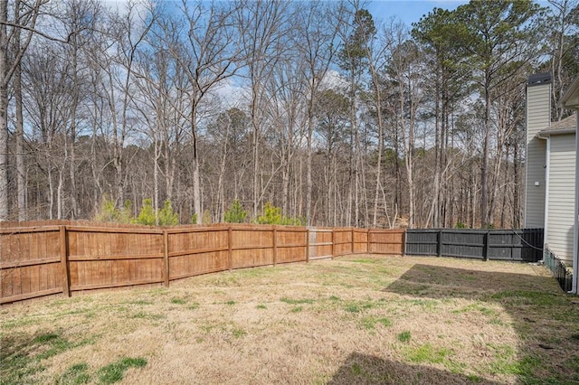 view of yard with a wooded view and a fenced backyard