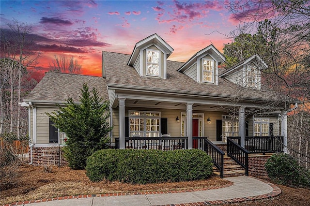 new england style home with covered porch and a shingled roof