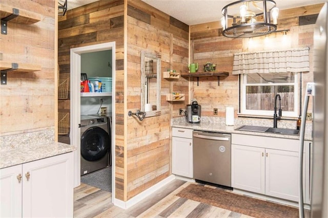 kitchen featuring white cabinets, washer / dryer, wood walls, and appliances with stainless steel finishes