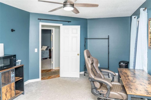 carpeted office featuring a textured ceiling and ceiling fan