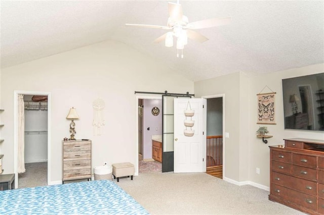 bedroom featuring a walk in closet, a barn door, and light carpet