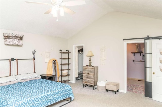 bedroom featuring lofted ceiling, a barn door, a spacious closet, light colored carpet, and a closet