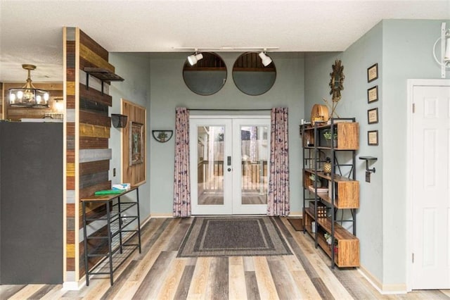 entrance foyer with a notable chandelier, hardwood / wood-style flooring, and french doors