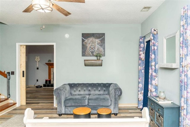 living room featuring ceiling fan, dark hardwood / wood-style floors, and a textured ceiling